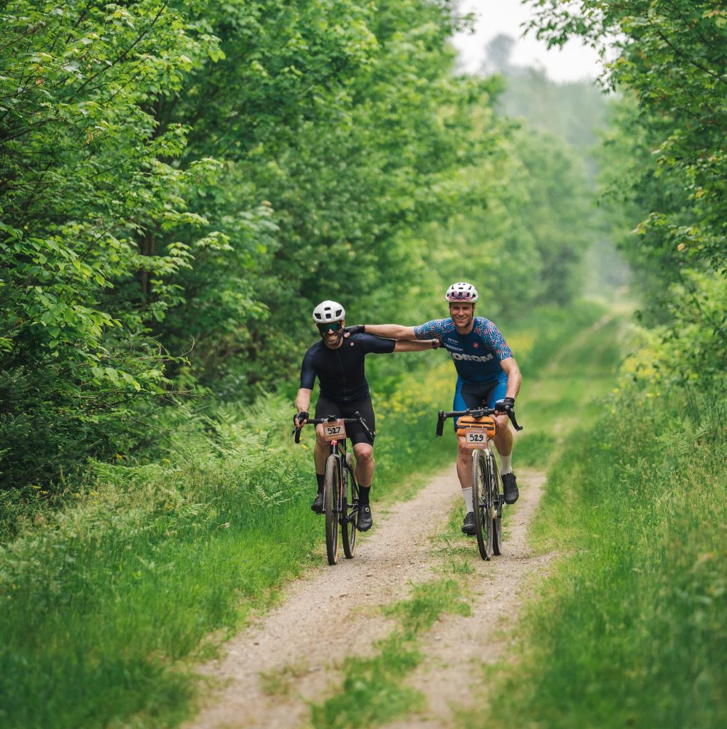 Deux cyclistes de gravelle dans la forêt qui se tiennent côté à côté par l'épaule